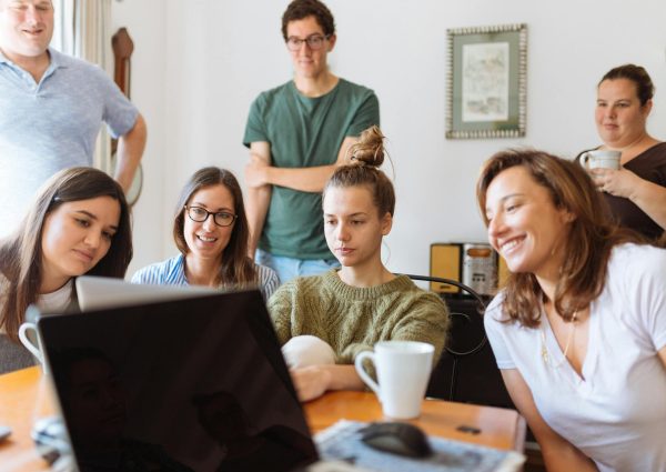 A diverse group of adults at work, enjoying a casual meeting indoors with focus and smiles.